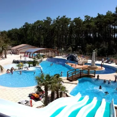 Piscine avec toboggan et palmiers au Camping Soulac Plage