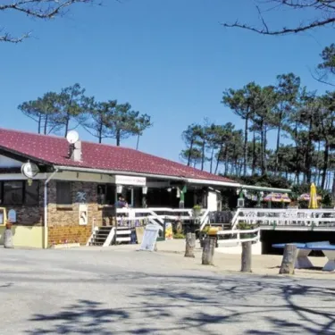 Bâtiment du camping avec terrasse et arbres en arrière-plan