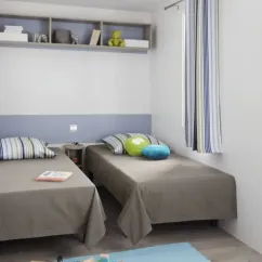 Mobil Home Mercure 2Ch – 4P - Camping du Val : Chambre avec 2 lits simples et étagères
