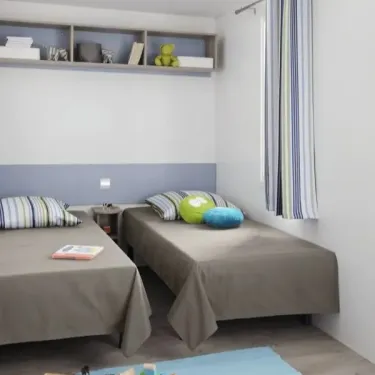 Mobil Home Mercure 2Ch – 4P - Camping du Val : Chambre avec 2 lits simples et étagères