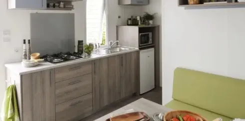 Mobil Home Mercure 2Ch – 4P - Camping du Val : cuisine moderne avec plan de travail et table à manger