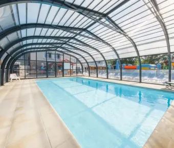 Piscine intérieure sous abri vitré avec bord de piscine en carrelage à Camping Paradis Les Chanterelles