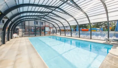 Piscine intérieure sous abri vitré avec bord de piscine en carrelage à Camping Paradis Les Chanterelles