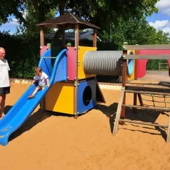 Enfant qui descend une slide dans un parc de jeux en sable au Camping La Bollée d'Air