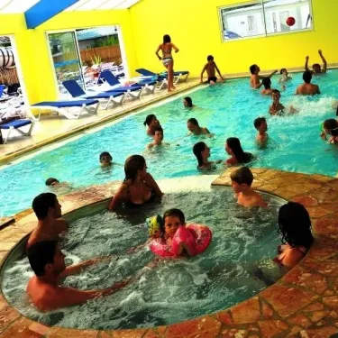 Piscine intérieure avec jacuzzi et enfants nageant au Camping La Bollée d'Air