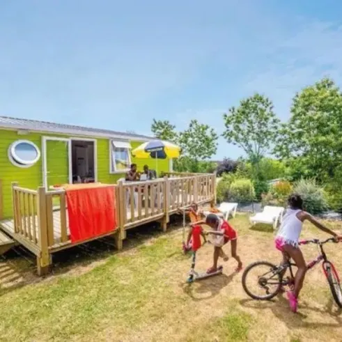 MH Classique 2CH – 4/5P (Mer) - Camping Paradis Domaine de Bel Air, mobil-home vert avec enfants sur pelouse