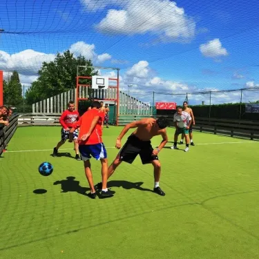 Enfants jouant au football sur un terrain en herbe à Camping La Bollée d'Air