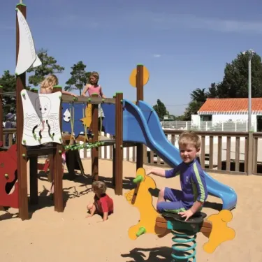 Enfants jouant sur un parcours de jeux en bois avec toboggan bleu et structure marine, Camping Zagarella.
