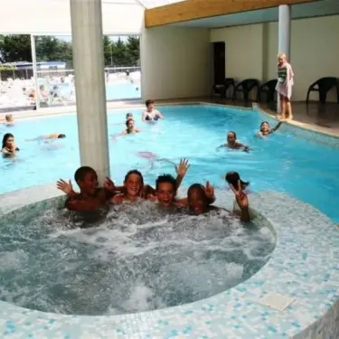 Enfants souriants dans une baignoire à remous en salle couverte, Camping Zagarella.