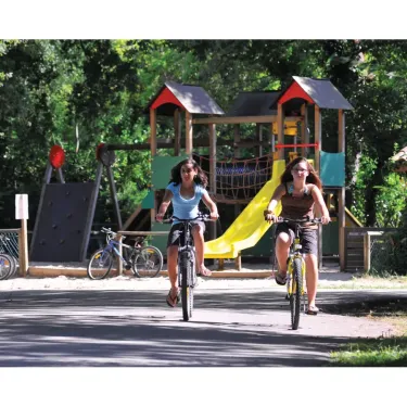 Enfants qui font du vélo près d'un parc infantile au Camping Eurolac.
