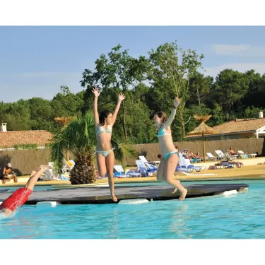 Deux filles sautent dans la piscine depuis une plateforme au Camping Eurolac.