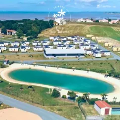 Vue aérienne du camping avec piscine ovale et cabanes autour