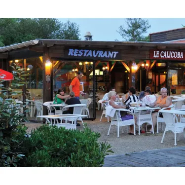 Le restaurant Le Calicoba avec des clients assis à l'extérieur sous un ciel crépusculaire.