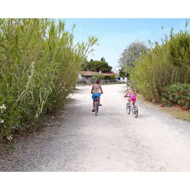 Deux enfants qui pédalent sur un chemin de gravier à Camping Les Fontaines