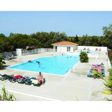 Piscine avec chaises longues et enfants nageant au Camping Les Fontaines