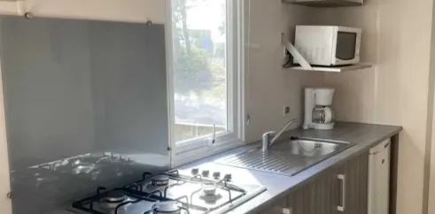 Mobil Home Primeo S 2CH - Camping Les Sables d'Argent : cuisine équipée avec four à gaz et micro-ondes