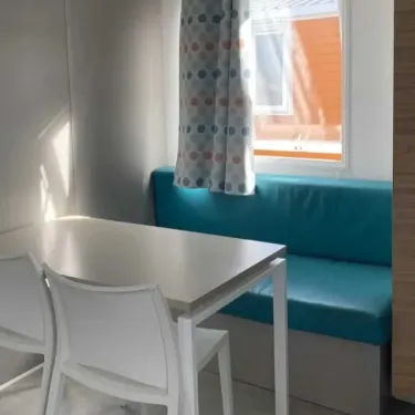 Mobil Home Cote Ouest S 2CH - 4P - Camping Les Sables d'Argent : coin repas avec canapé bleu