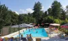 Personnes dans la piscine avec parasols colorés et chaises longues autour au Camping de la Colombière
