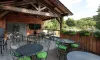 Camping de la Colombière - terrasse en bois avec tables et chaises vertes sous abri en bois