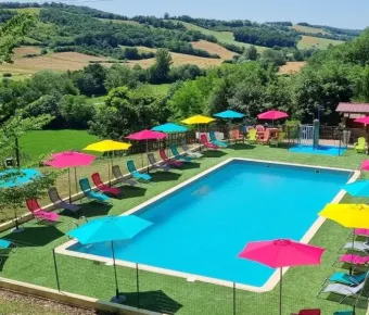 Piscine colorée entourée d'ombrelles et de chaises longues au Camping Le Bourdieu