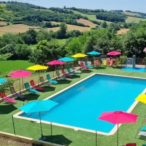 Piscine colorée entourée d'ombrelles et de chaises longues au Camping Le Bourdieu