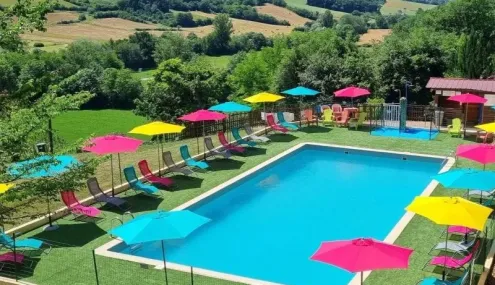 Piscine colorée entourée d'ombrelles et de chaises longues au Camping Le Bourdieu