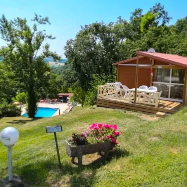 Cabane en bois avec balcon et jardin fleuri près de la piscine au Camping Le Bourdieu