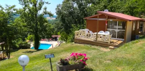 Cabane en bois avec balcon et jardin fleuri près de la piscine au Camping Le Bourdieu