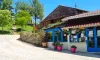 Camping Le Bourdieu - boutique en bois avec toit rouge et pots roses