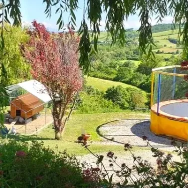 Camping Le Bourdieu - Vue sur les collines avec trampoline et cabane