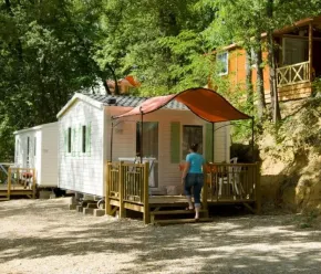 Cottage Duo 2P - Camping Le Bourdieu : cabane avec toit rouge et personne entrant