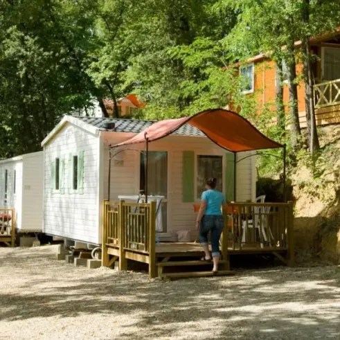 Cottage Duo 2P - Camping Le Bourdieu : cabane avec toit rouge et personne entrant