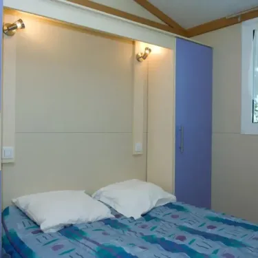 Chambre avec lit double et armoire bleue dans Cottage 2CH - 5P - Camping Le Bourdieu
