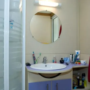 Cottage 2CH - 5P - Camping Le Bourdieu : salle de bains avec lavabo et miroir rond