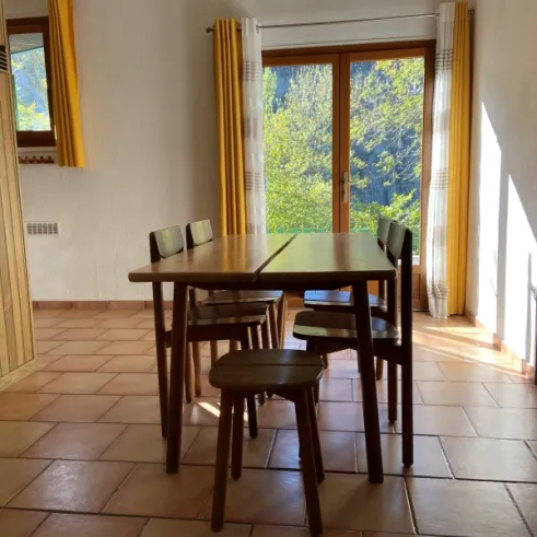 Table à manger avec chaises et fenêtre donnant sur la nature - Cottage Confort 2 Chambres - Camping Village de Vacances Camboussel