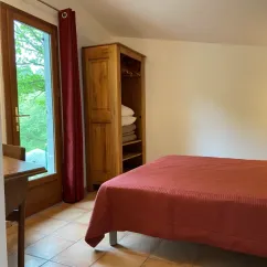 Chambre avec lit double, armoire en bois, fenêtre et rideau rouge - Cottage Confort 2 Chambres - Camping Village de Vacances Camboussel