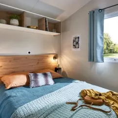 Mobil Home Bahia Confort+ 2CH - 4P - Camping La Frétille, lit avec couverture et plantes