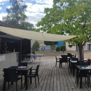 Terrasse extérieure du camping Val de Braye avec tables et chaises sous une bâche