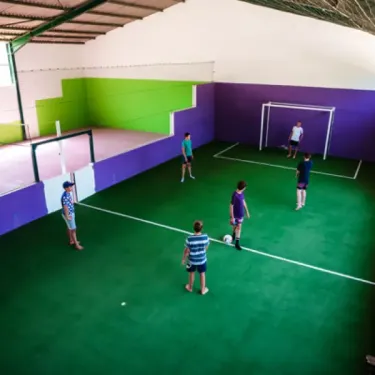 Enfants jouant au football dans une salle de sport à Camping La Cascade