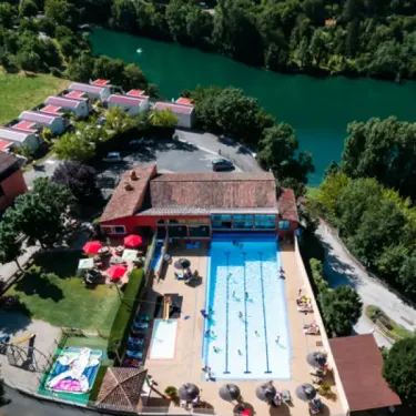 Camping La Cascade - piscine en plein air avec personnes nageant, bordée d'ombrelles