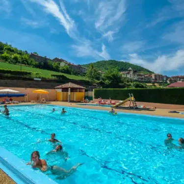 Camping La Cascade - piscine avec enfants nageant sous un ciel bleu