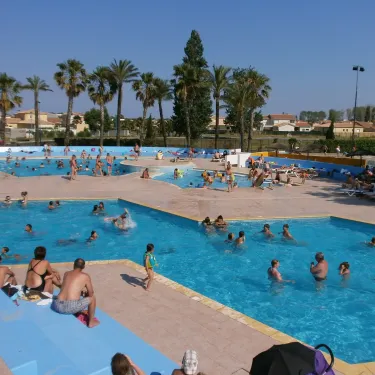 Piscine extérieure animée avec des visiteurs nageant et se détendant autour, au Camping Bosc d'En Roug.