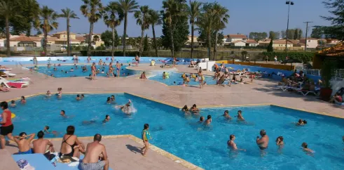 Piscine extérieure animée avec des visiteurs nageant et se détendant autour, au Camping Bosc d'En Roug.