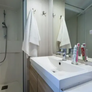 Salle de bain avec lavabo, douche et serviettes blanches - MH Classique 3CH - Camping Bel Air Village Le Plan d'eau