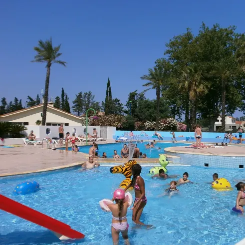 Enfants jouent dans une piscine avec toboggan et flottants colorés au Camping Bosc d'En Roug.