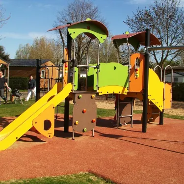 Piste de jeux pour enfants au Camping Le Curtys avec toboggan jaune et structures colorées.