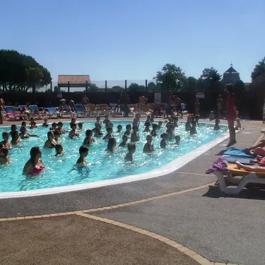Piscine extérieure du Camping Le Curtys avec enfants et chaises longues.