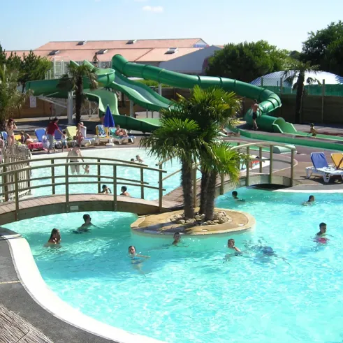 Piscine avec toboggan vert et palmiers au Camping Le Curtys