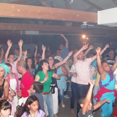 Groupe de personnes dansant joyeusement lors d'une soirée festive au Camping Le Curtys.