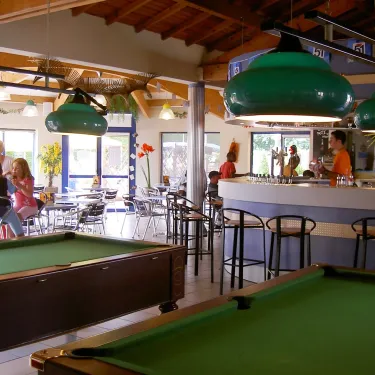 Intérieur du camping Le Curtys avec billard et bar, ambiance détendue.